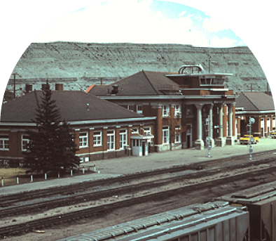 Historic train station with brick building and multiple tracks.