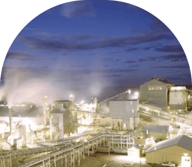 Industrial plant at night with illuminated buildings and pipelines.