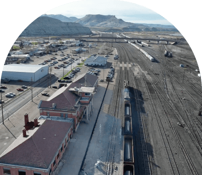 Aerial view of a train station with tracks and surrounding buildings under cloudy skies.