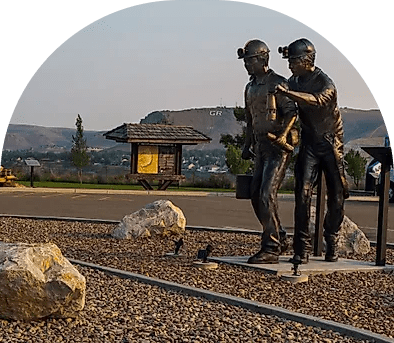 Bronze sculpture of two children playing with a ball outdoors.