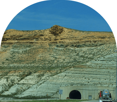 A scenic mountain landscape with a tunnel entrance at the base.