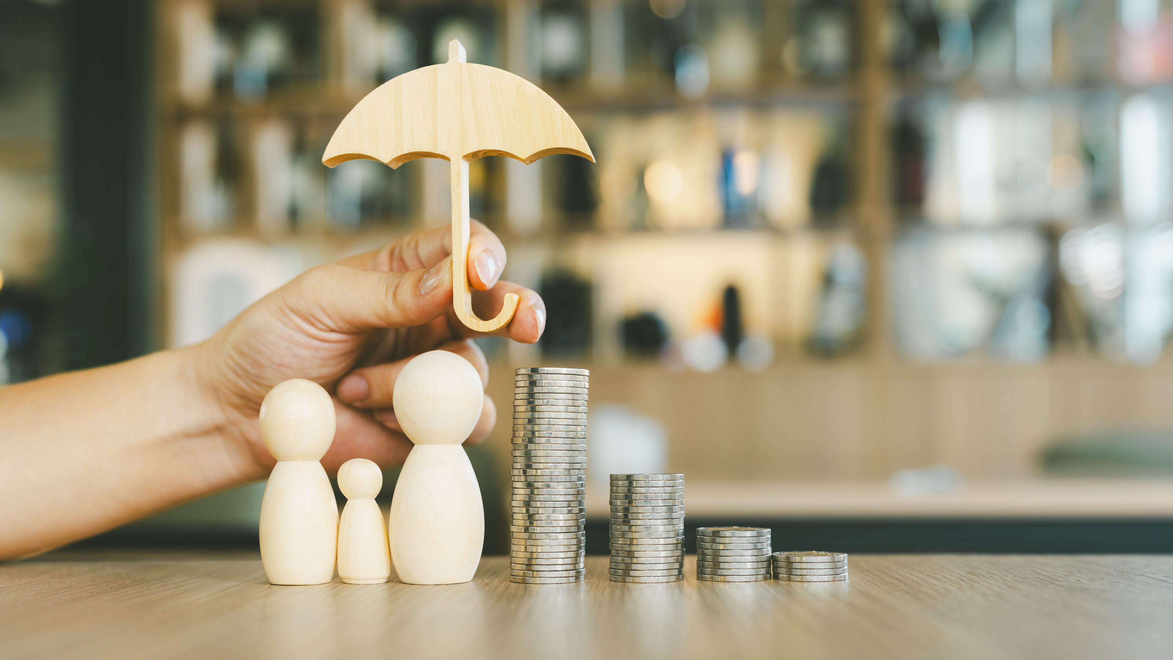Wooden figures, umbrella, stacked coins on table.