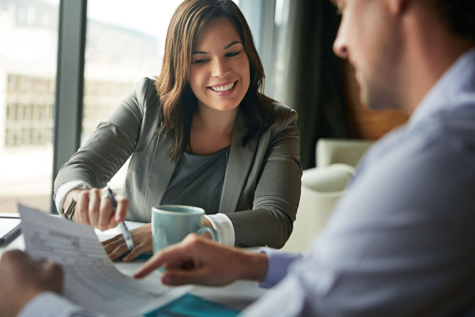 Two people discussing documents over coffee.