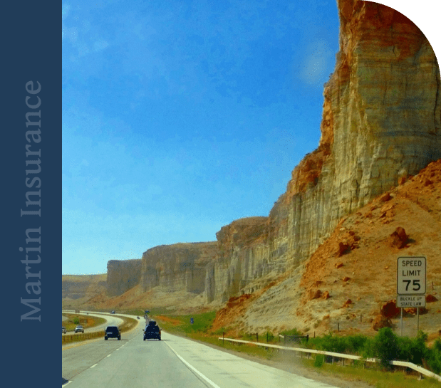 Scenic highway with red rock cliffs under a bright blue sky.